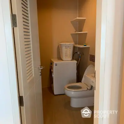 Compact bathroom with washing machine and toilet, featuring modern shelving.