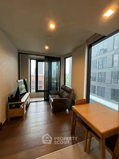 Modern living room with city view, featuring sleek furniture and large windows.