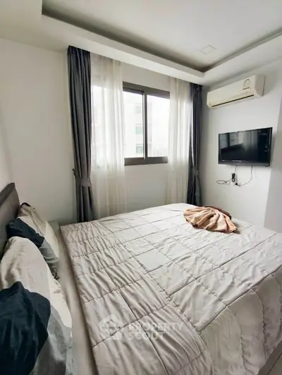 Cozy bedroom with modern decor, featuring a wall-mounted TV and air conditioning, perfect for relaxation.