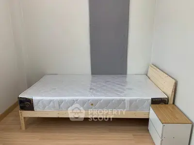Minimalist bedroom with wooden bed frame and nightstand, perfect for cozy living.