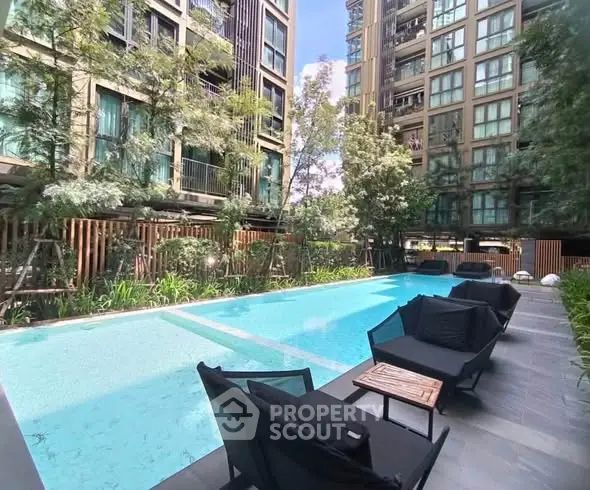 Luxurious apartment complex with a stunning outdoor pool and modern seating area.