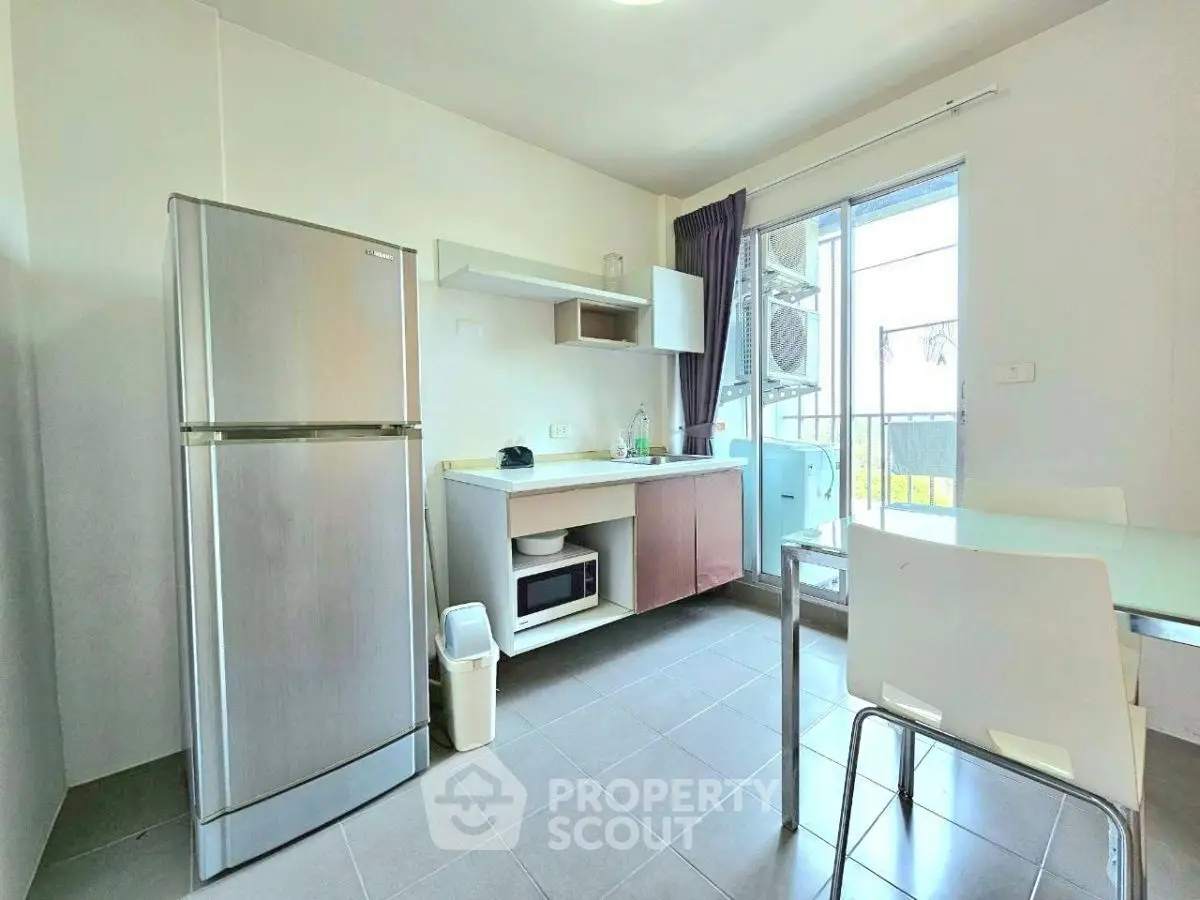 Modern kitchen with stainless steel fridge and microwave, featuring open layout and balcony access.