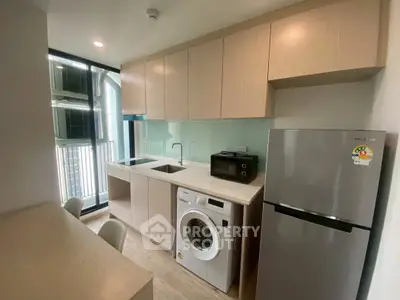 Modern kitchen with washing machine and fridge in sleek apartment