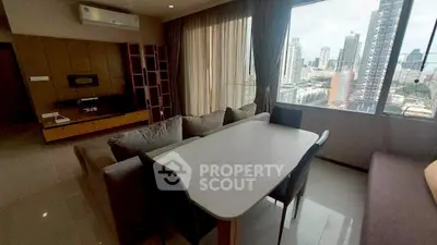 Modern living room with city view, featuring a sleek dining table and comfortable sofa.