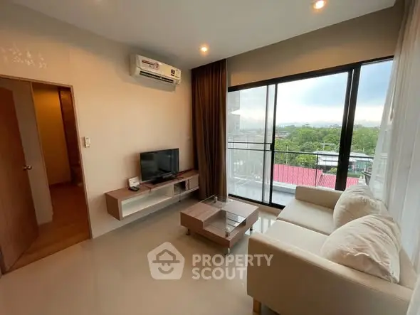 Modern living room with large windows and cozy furniture, offering a serene view.