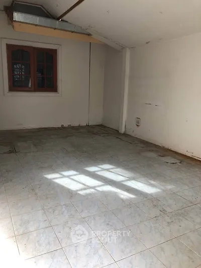 Spacious empty room with tiled floor and window, ideal for customization.