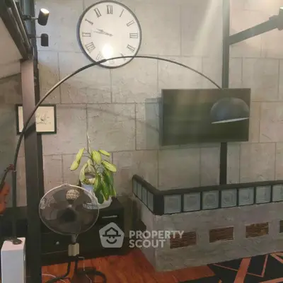 Stylish living room with modern decor, featuring a large clock, sleek lamp, and contemporary TV setup.