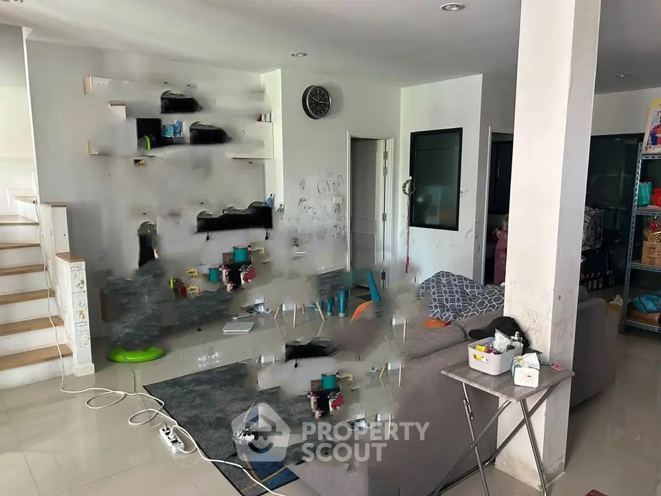 Spacious living room with modern decor and open layout, featuring a cozy sofa and stylish shelving.