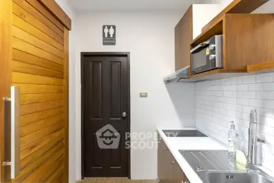 Modern compact kitchen with wooden sliding door and restroom sign
