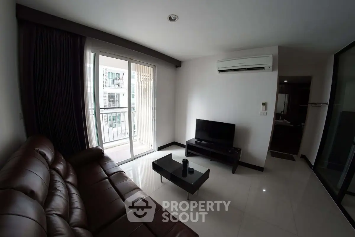 Modern living room with leather sofa, TV, and balcony access in a stylish apartment.