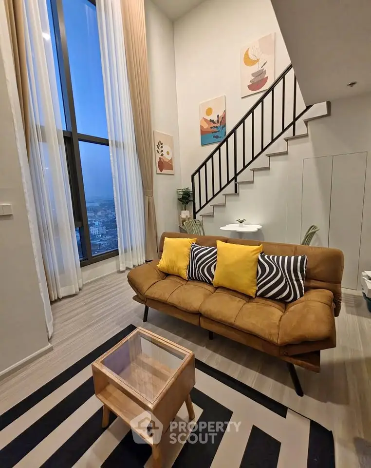 Modern living room with high ceilings, stylish decor, and large windows offering city views.