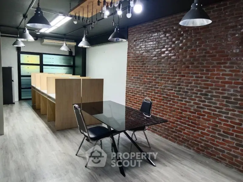 Modern industrial office space with exposed brick wall and sleek lighting fixtures.