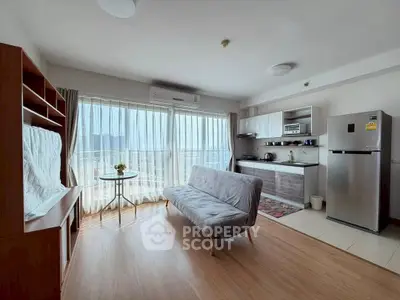 Modern open-layout living room with kitchen, featuring large windows and stylish furniture.