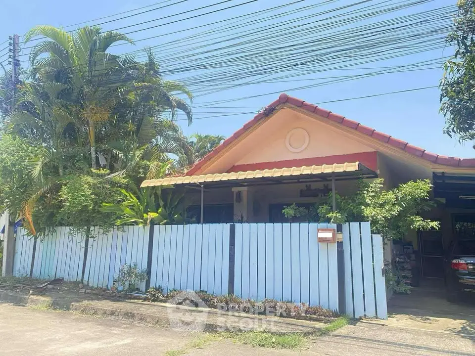 Charming single-story home with lush garden and blue fence in a serene neighborhood.
