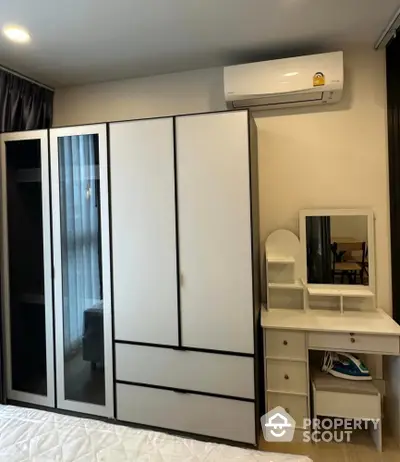 Modern bedroom with sleek wardrobe and vanity set, featuring air conditioning for comfort.