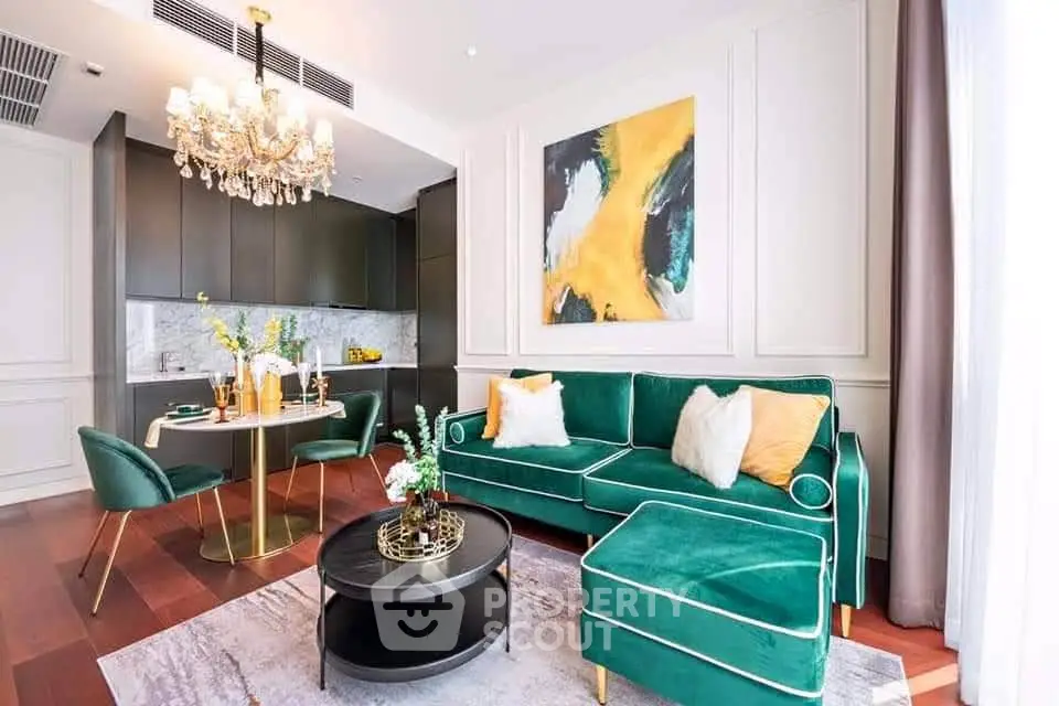 Luxurious living room with emerald green sofa, elegant chandelier, and modern kitchen in open layout.