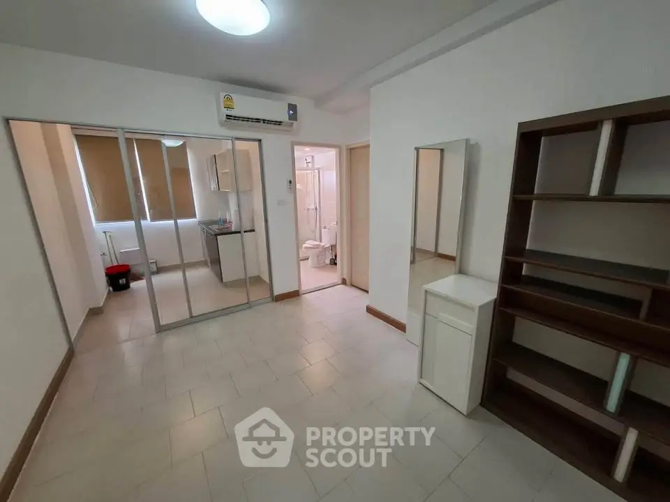 Spacious room with modern shelving and bathroom access in a well-lit apartment.
