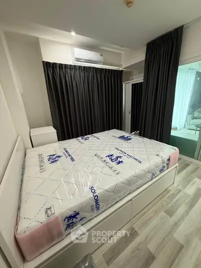 Modern bedroom with sleek design and large window, featuring a new mattress and stylish flooring.