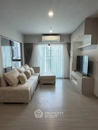 Spacious modern living room with large windows and stylish furniture in a high-rise apartment.