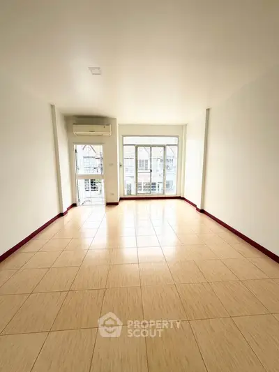 Spacious empty living room with large windows and tiled flooring, perfect for customization.