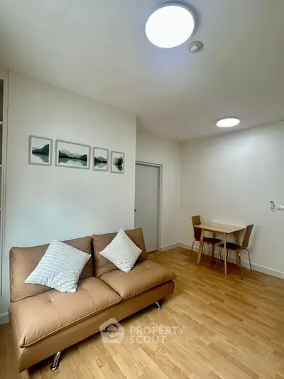 Modern living room with cozy sofa and dining area, featuring stylish decor and wooden flooring.