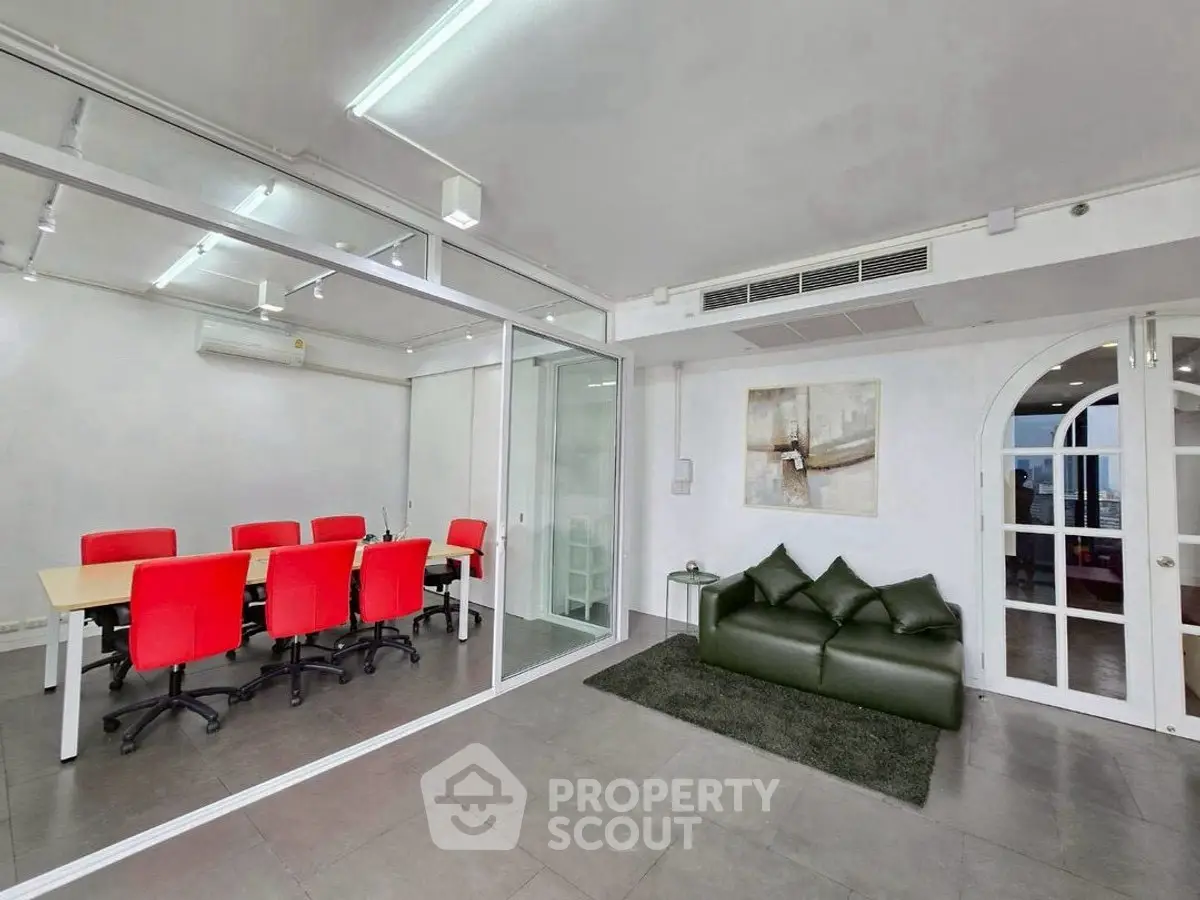Modern office space with glass walls and red chairs in a sleek conference room.