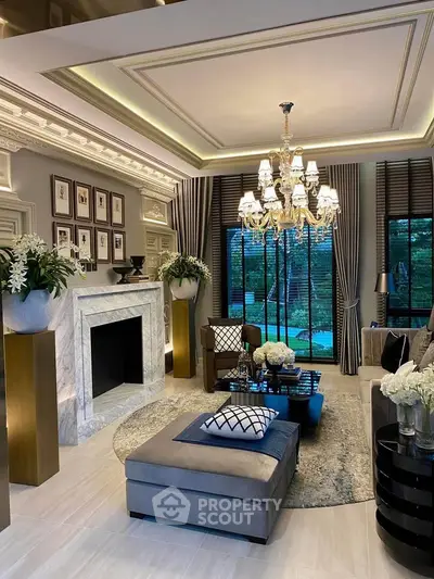 Luxurious living room with elegant chandelier and marble fireplace, featuring large windows and stylish decor.