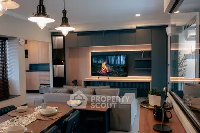 Modern living room with stylish decor and open kitchen layout, featuring a cozy fireplace on TV.