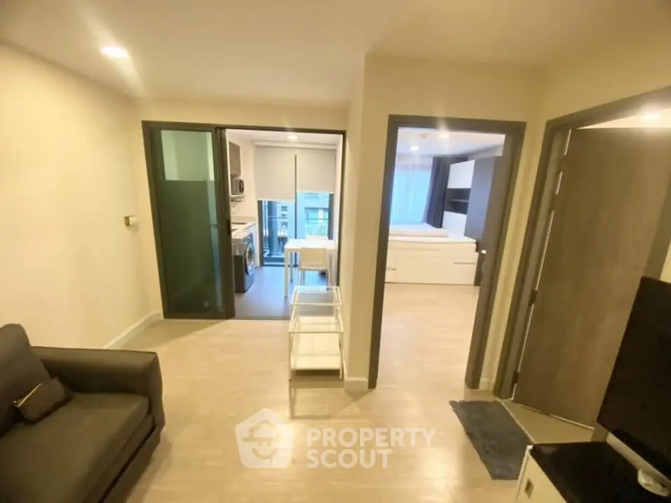 Modern apartment interior with open layout, featuring a cozy living area and a glimpse of the kitchen and bedroom.