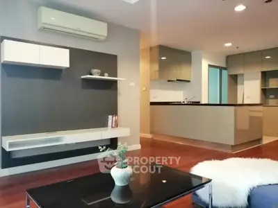 Modern open-plan living space with sleek kitchen, featuring warm wooden flooring, contemporary furniture, and a cozy ambiance perfect for urban living.
