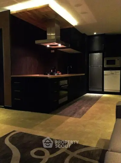Modern kitchen with sleek dark cabinetry and built-in appliances, featuring a stylish open layout.