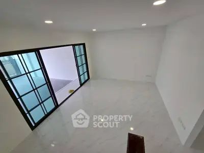 Spacious empty room with sliding glass doors and marble flooring