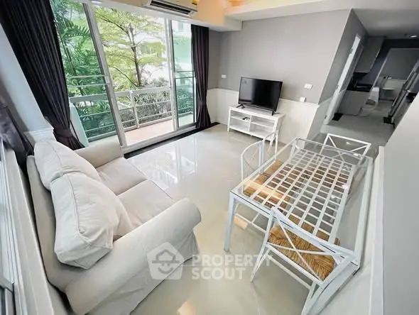 Modern living room with sleek furniture and large windows overlooking greenery.