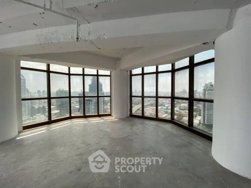 Spacious corner unit with panoramic city views through large windows in a high-rise building.