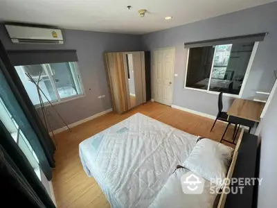 Spacious bedroom with polished wooden flooring, modern furnishings, ample natural light, and a cozy ambiance, perfect for relaxation and comfort.