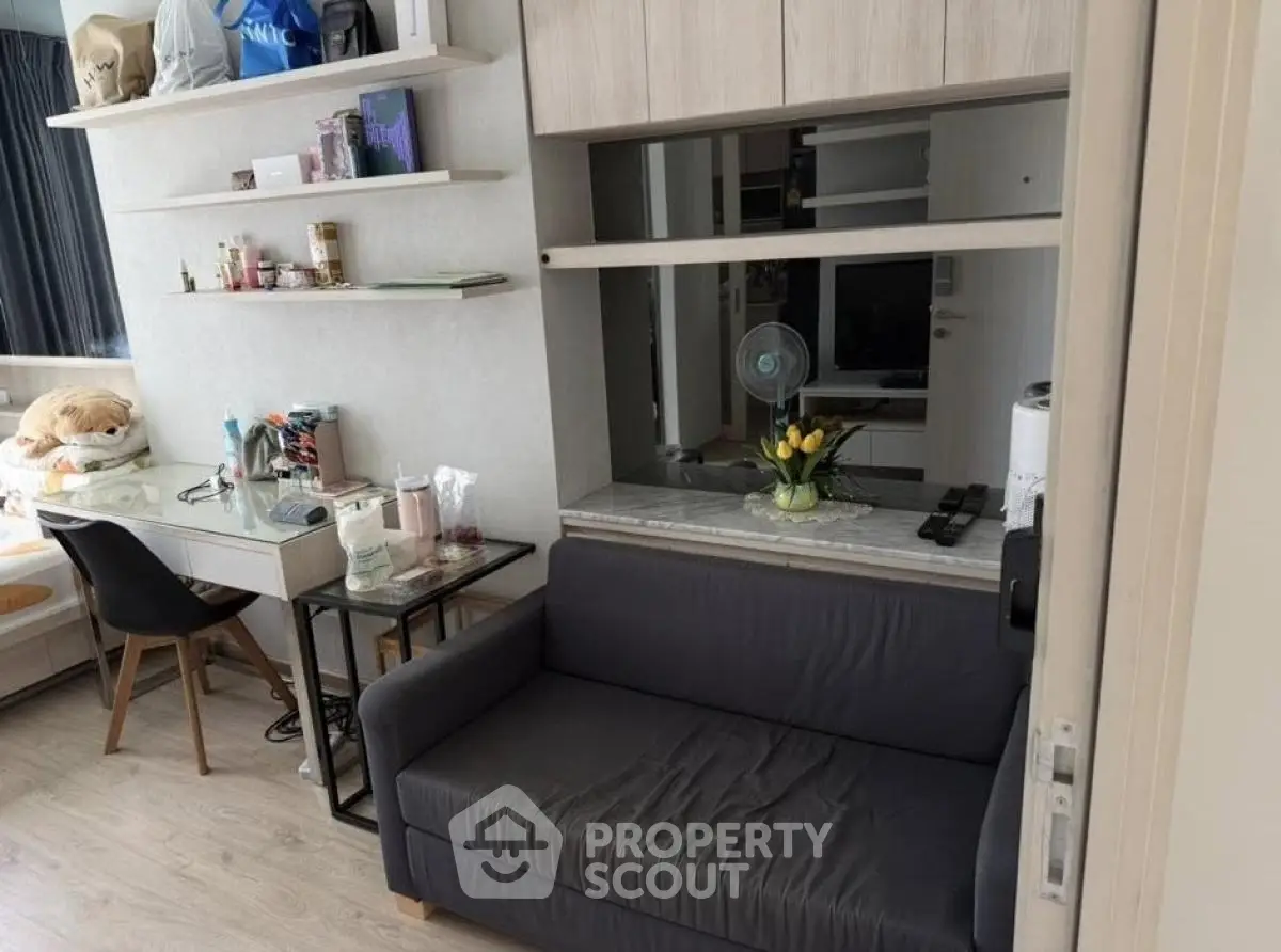 Cozy living room with modern decor and workspace, featuring a plush sofa and stylish shelving.