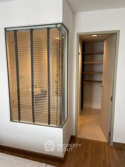 Modern interior with wooden flooring and glass partition, featuring a walk-in closet.