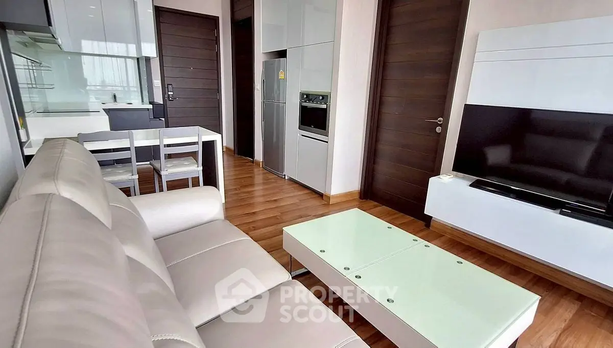 Modern living room with sleek furniture and open kitchen layout in a stylish apartment.