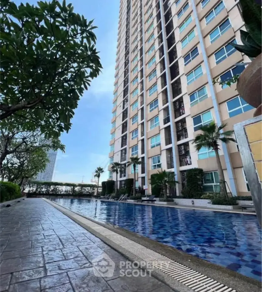 Luxurious high-rise building with stunning poolside view and lush greenery.
