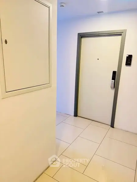 Modern apartment entrance with sleek white door and tiled flooring