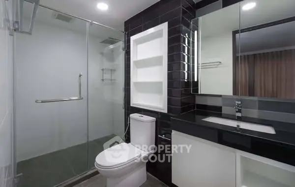 Modern bathroom with sleek black tiles and glass shower enclosure