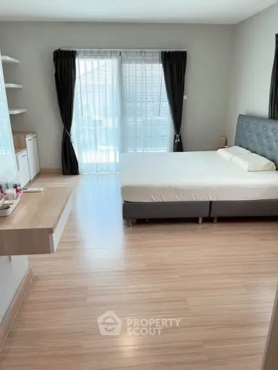 Spacious bedroom with modern decor and large windows for natural light.