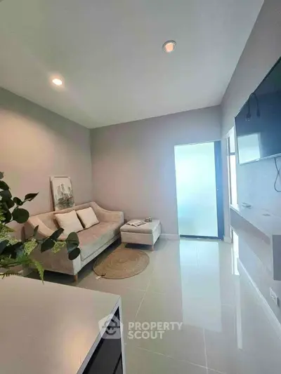 Modern living room with sleek design, featuring a cozy sofa, wall-mounted TV, and minimalist decor.