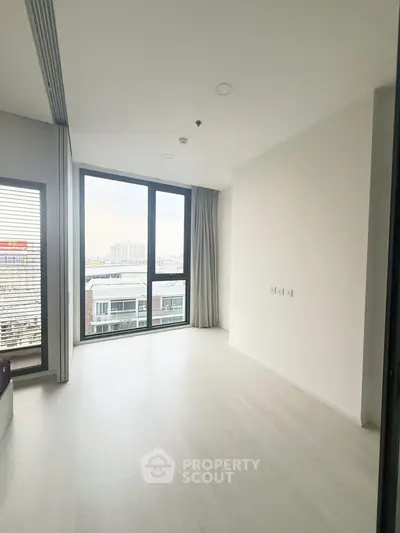 Spacious modern living room with large windows and city view, perfect for urban living.