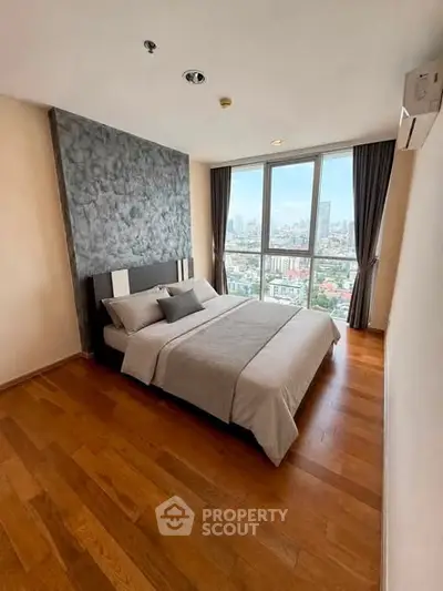 Modern bedroom with city view, featuring wooden flooring and stylish decor.