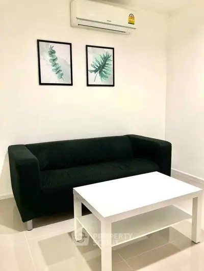 Modern living room with black sofa, white coffee table, and minimalist decor.
