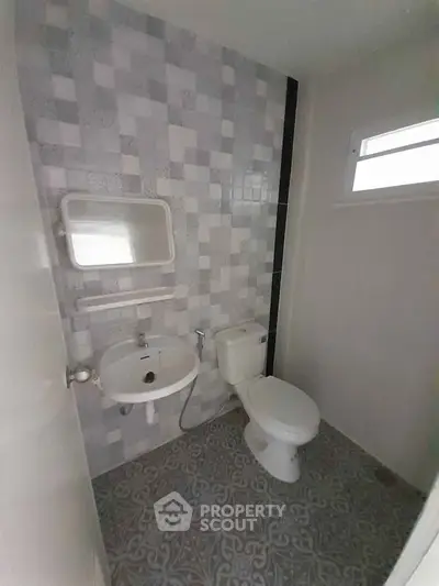 Compact bathroom with modern tiling and essential fixtures.