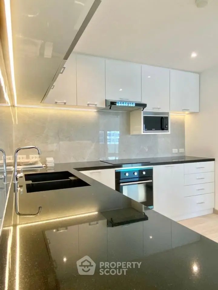 Modern kitchen with sleek black countertops and built-in appliances in a stylish apartment.