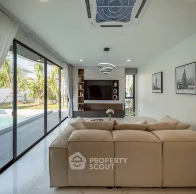 Luxurious living room with pool view, modern decor, and large beige sofa in a stylish home.