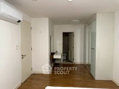 Modern bedroom with wooden flooring, built-in wardrobe, and air conditioning unit.